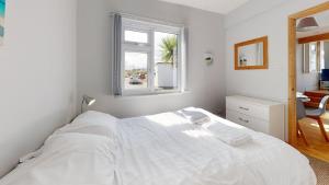 a white bedroom with a large bed and a window at C23 Wilmar, Riviere Towans in Hayle