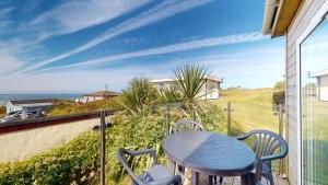 a table and chairs on a balcony with a view of the ocean at C23 Wilmar, Riviere Towans in Hayle +6 photos