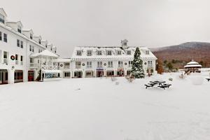 a large white building with a snow covered courtyard at Waterville Vacation Condo in Waterville Valley