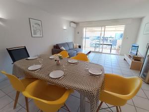 a dining room with a table and yellow chairs at Apartment Le Magellan-2 by Interhome in Saint-Raphaël