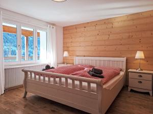 a bedroom with a large bed with a wooden wall at Holiday Home Chalet Ahornen by Interhome in Grindelwald