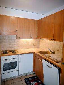 een keuken met houten kasten, een wit fornuis en een wastafel bij Centre Thermal NORD studio TH203 in Ovronnaz