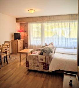 een slaapkamer met een bed, een tafel en een televisie bij Centre Thermal NORD studio TH203 in Ovronnaz