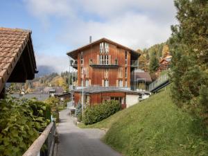 a large wooden house on a hill next to a road at Apartment Schweizerheim Apt-5 by Interhome in Wengen