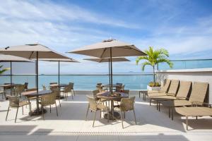 un patio avec des tables et des parasols et l'océan dans l'établissement Hotel Atlantico Praia, à Rio de Janeiro