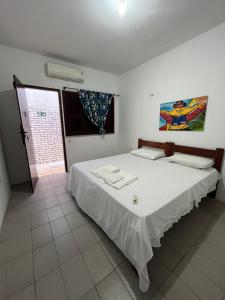 a bedroom with a large white bed and a window at Pousada Rosa Mistica in Paracuru