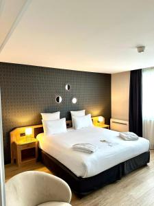 Una habitación de hotel con una cama grande y una silla. en Best Western Plus Le Picardy, en Saint-Quentin