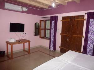 a bedroom with a bed and a tv and a table at Southcanal Holidays in Alleppey
