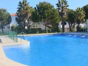 Una gran piscina azul con árboles al fondo. en Casa Hortensia, en Chiclana de la Frontera