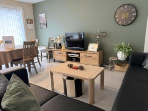 a living room with a couch and a tv and a table at Apartment Westhinder with balcony by Interhome in Blankenberge