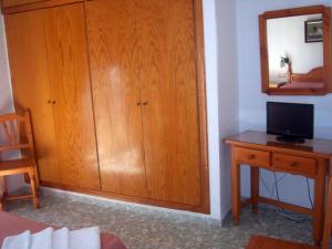 a room with a wooden cabinet and a desk with a television at Pensión Felipe in Carboneras