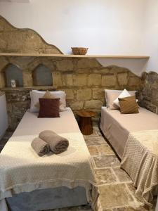 two beds in a room with a stone wall at 'I Elea' Village House with Courtyard in Letimbou