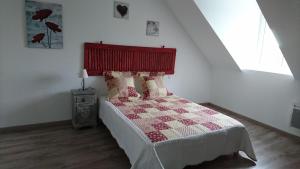 1 dormitorio con 1 cama con edredón rojo y blanco en Gîte de l'hamelinaie, en Montanel
