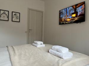 een slaapkamer met handdoeken op een bed met een tv aan de muur bij Mountain Place to Remember - River & Barbecue in Buşteni