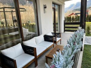een veranda met twee witte banken en een tafel bij Mountain Place to Remember - River & Barbecue in Buşteni