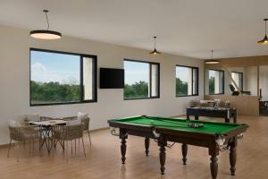 The Fern Vishranta Resort, Kamrej-Surat, Series by Marriott في سورات: غرفة مع طاولة بلياردو وكراسي ونوافذ
