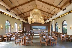 The Fern Vishranta Resort, Kamrej-Surat, Series by Marriott في سورات: غرفة طعام مع طاولات وكراسي وثريا