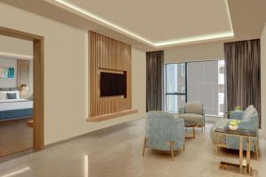 Una sala de estar con un sofá y sillas y un televisor. en The Fern Residency Bengaluru, Seshadripuram, Series by Marriott, en Bangalore
