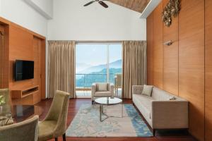 uma sala de estar com um sofá e uma janela grande em The Fern Surya Resort Kasauli Hills, Dharampur, Series by Marriott em Kasauli