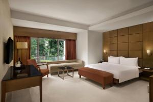 a bedroom with a bed and a couch and a desk at The Fern Residency Woodland, Pune, Series by Marriott in Pune