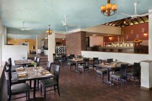 a dining room with tables and chairs and a bar at The Fern Samali Resort Dapoli, Series by Marriott in Dapoli