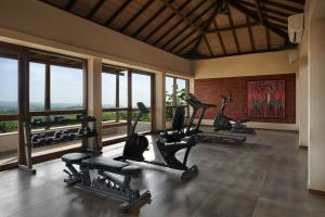 a gym with treadmills and ellipticals in a room with windows at The Fern Samali Resort Dapoli, Series by Marriott in Dapoli
