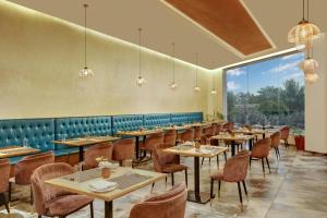 Un restaurante con mesas y sillas y un gran ventanal. en The Fern Residency, Jamnagar, Series by Marriott, en Jamnagar