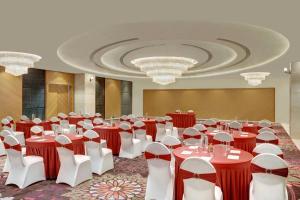 un salón de banquetes con mesas y sillas rojas y blancas en The Fern Residency, Jamnagar, Series by Marriott, en Jamnagar