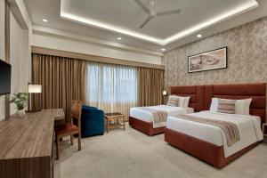 a hotel room with two beds and a desk at The Fern Residency, Bodhgaya, Series by Marriott in Bodh Gaya