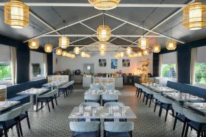 The Fern Seaside Luxurious Tent Resort Daman, Series by Marriott في دامان: غرفة طعام بطاولات بيضاء وكراسي وثريات