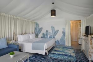 The Fern Seaside Luxurious Tent Resort Daman, Series by Marriott في دامان: غرفة فندق بها سرير وأريكة
