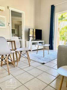 Villa Le Coin - T2 moderne climatisé avec Wi-Fi في Midlands Station: غرفة معيشة مع طاولة وكراسي وتلفزيون