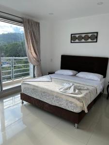 Una cama en un dormitorio con una ventana grande. en Apartamento con Piscina y Vista panoramica Anapoima Centro, en Anapoima