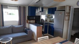 een keuken met blauwe kasten, een bank en een koelkast bij Julieregis in Biscarrosse