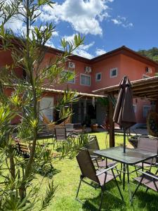 een terras met een tafel en stoelen voor een huis bij Pousada Refúgio das Flores in Ubatuba