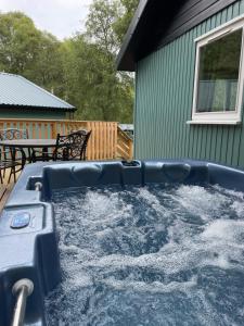 a hot tub with water in it in front of a house at Bracken Lodge 8 with Hot Tub in Belladrum
