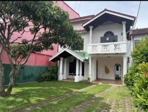 una casa rosa e bianca con un albero nel cortile di Royal Wings Villa a Negombo