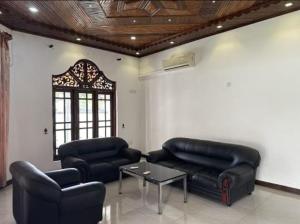 un soggiorno con mobili in pelle nera e un tavolo di Royal Wings Villa a Negombo