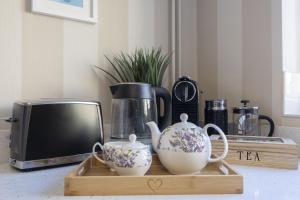 een houten dienblad met twee theekopjes en een magnetron bij Charming Cotswold Cottage in Central Winchcombe in Winchcombe