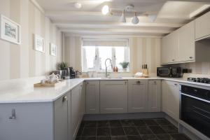 een keuken met witte kasten, een gootsteen en een raam bij Charming Cotswold Cottage in Central Winchcombe in Winchcombe +26 foto's