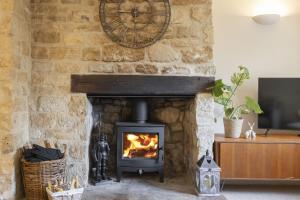 a fireplace with a stove in a stone wall at Charming Cotswold Cottage in Central Winchcombe in Winchcombe
