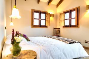ポンタ・ド・パールゴにあるCasas da Levadaのベッドルーム1室(ベッド1台、花のテーブル付)