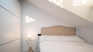 Un dormitorio con una cama blanca con una pared blanca. en William Martin Apartments, en Huelva