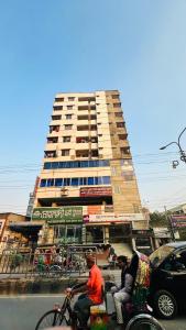 three people riding motorcycles in front of a tall building at Hotel Prime City Residential in Dhaka