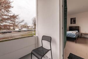 MK Apartments Delmenhorst nähe Bremen 1 في دلمنهورست: كرسي يجلس على شرفة تطل على نافذة
