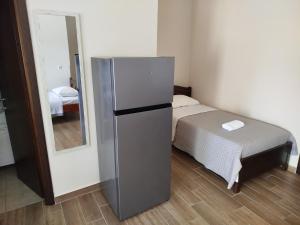 a refrigerator in a room with a bed and a mirror at Harmony Apartments in Larisa