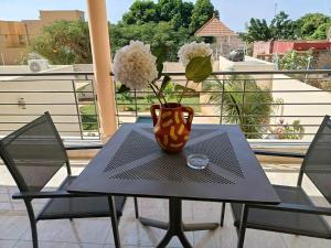 Les Studios de l'Oasis في Ngaparou: مزهرية على طاولة مع كرسيين على شرفة