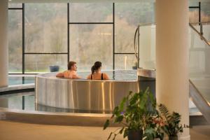 PogányHotel Essence的两个人泡在带大窗户的热水浴缸里