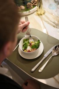 a person eating a plate of salad on a table at Hotel Essence in Pogány +170 photos
