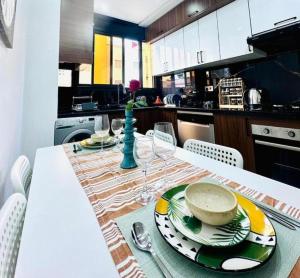Una cocina con una mesa con platos y vajilla encima. en Elegant 3BR Stay 5min to Hay Riad, en Temara 23 fotos más